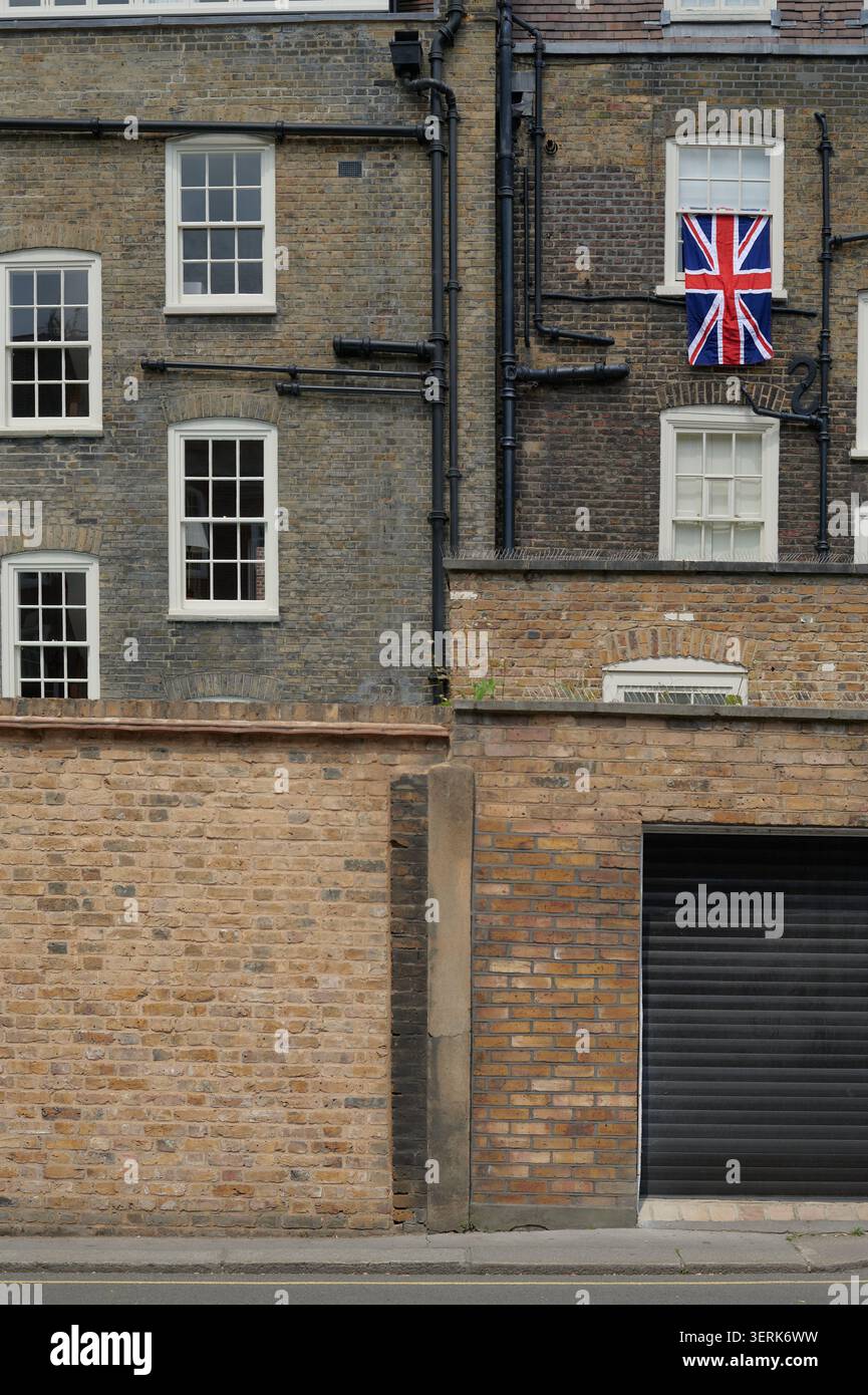 Union Jack Union Flag UK Flagge hängt am Fenster hinter dem alten Reihenhaus Stockfoto