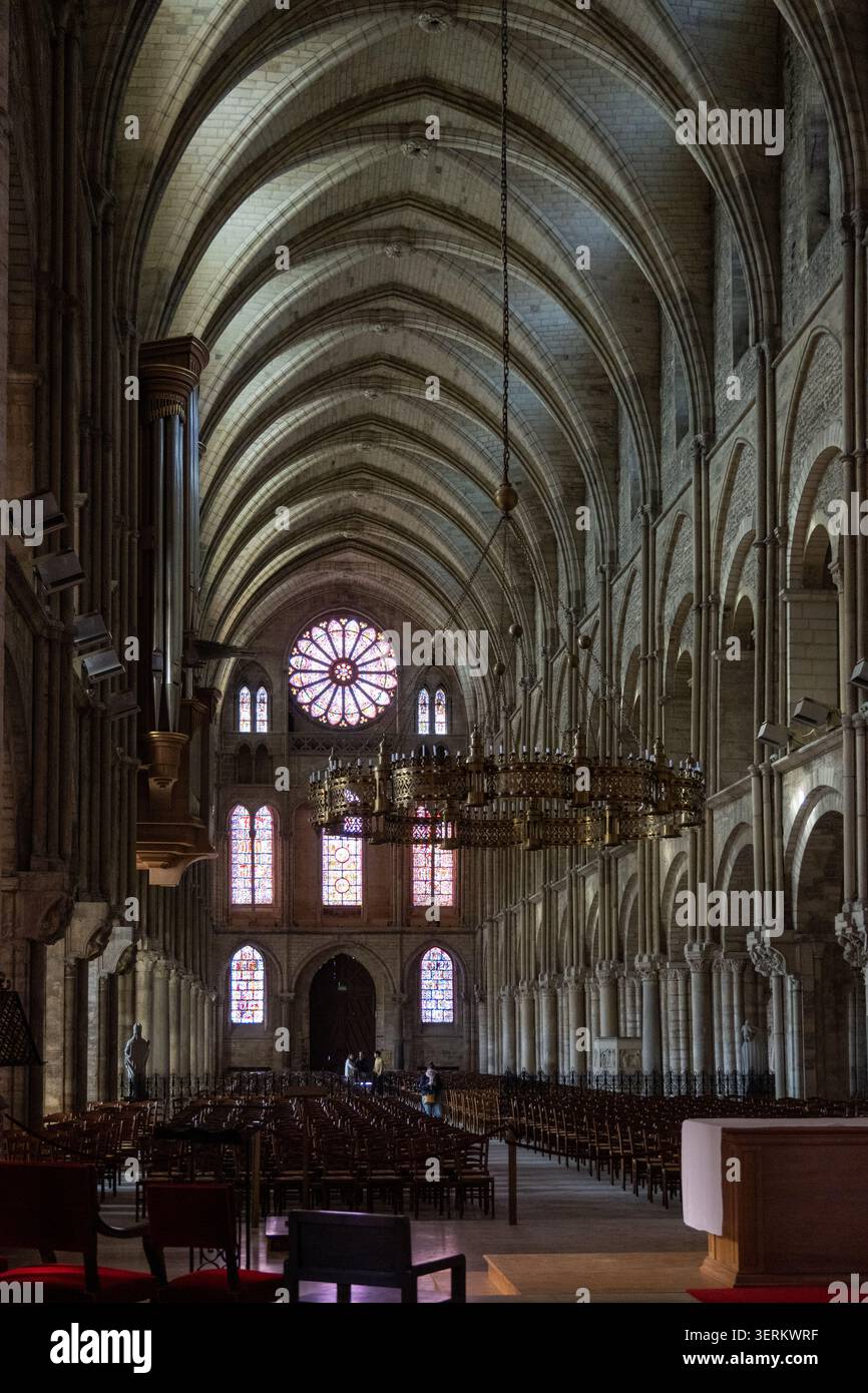 Blick auf das Schiff der Basilique Saint-Remi mit Rippengewölben, Kronleuchtern und Rosenfenster in Reims, Frankreich. Stockfoto