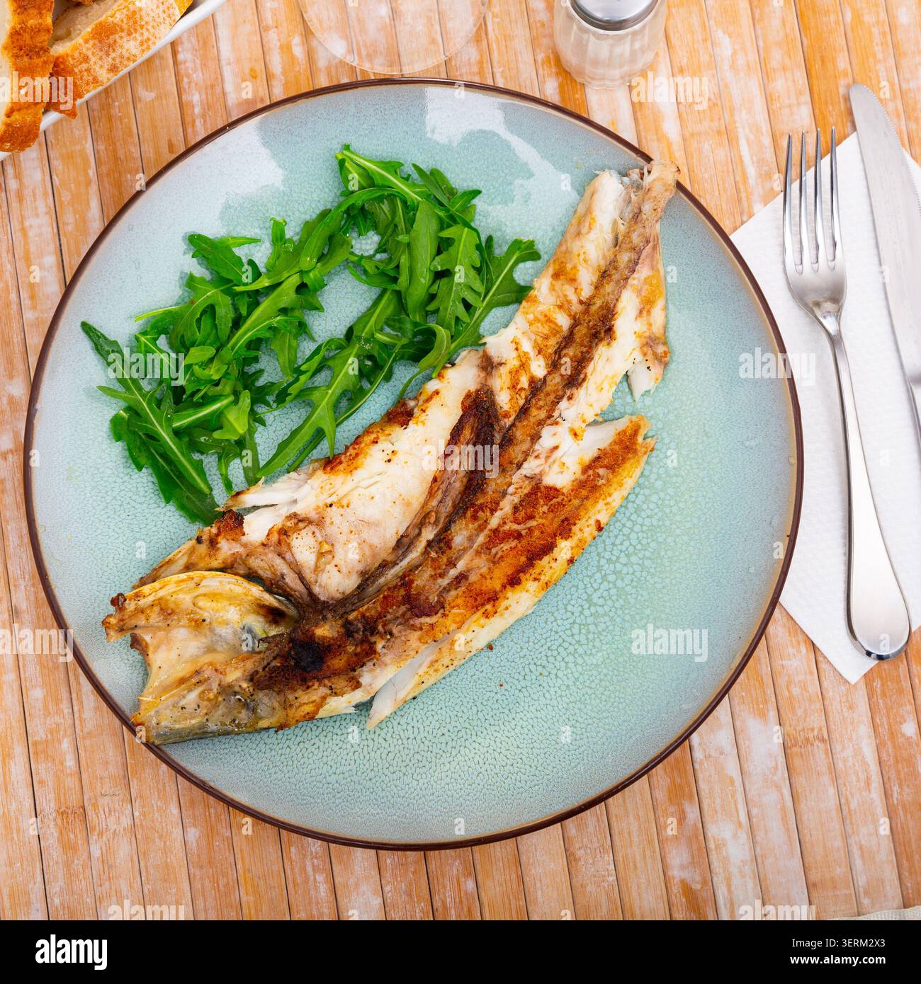 Frisch gebackener Fisch Seebarsch mit Rucola Stockfoto