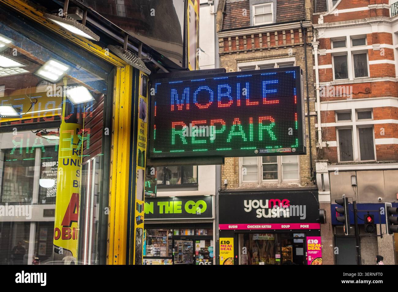 LONDON – 11. MAI 2026: Mobile Reparaturwerkstatt Brixton – LED-Schild „Mobile Repair“ vor einer kleinen High Street Tech Reparaturwerkstatt. Stockfoto