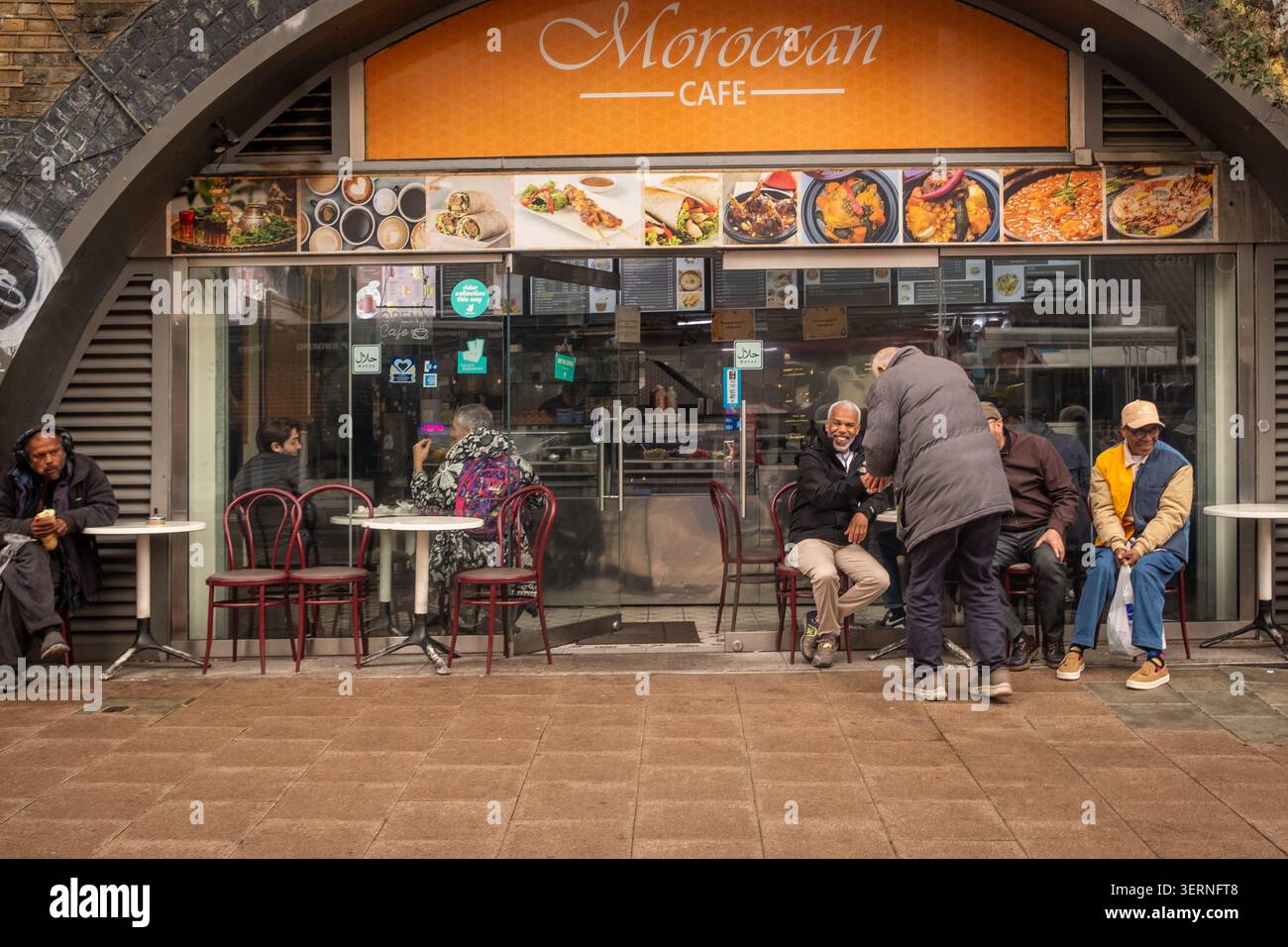 LONDON – 11. MAI 2026: Marokcan Cafe Brixton – Einheimische sitzen vor einem kleinen marokkanischen Café an der Brixton Station Road. Stockfoto
