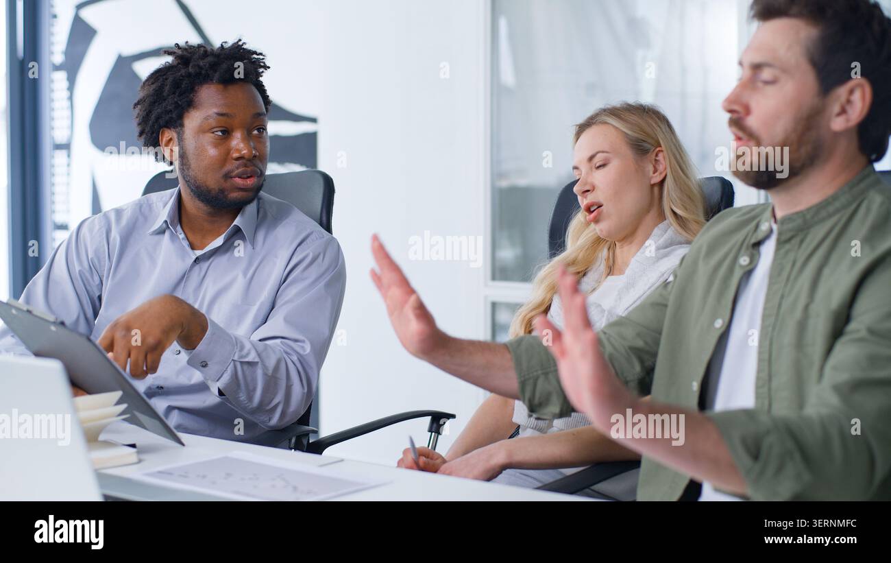 Internationale Geschäftsgruppe von drei Arbeitern diskutiert Papiere Problem afroamerikanischer Chef zeigt Ordner Tablett mit Dokumentdaten Kaukasischer Mann Stockfoto