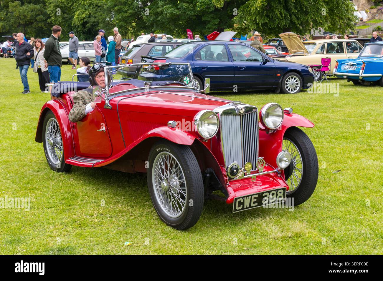 Red 1938 MG TA Midget Roadster mit Fahrer in Oldtimer-Helm und Schutzbrille auf einer Oldtimer-Ausstellung im Freien in Großbritannien Stockfoto