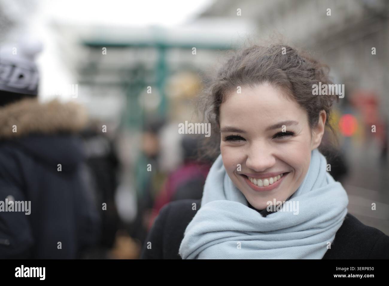 Glückliche junge Frau, die auf einer geschäftigen Straße lächelt Stockfoto