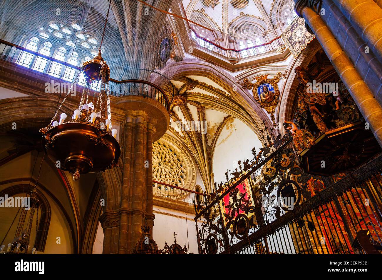 Gotische Gewölbe und kunstvoller goldener Kronleuchter im Kloster Guadalupe Stockfoto