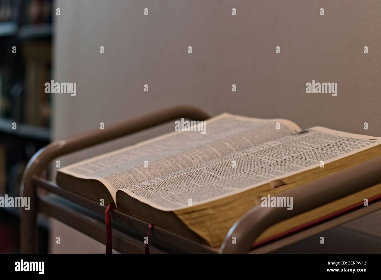 Offene Bibel, die auf einem Rednerpult der Kirche steht, steht in einem ruhigen Gotteshaus, das die Lektüre der Schriften, die Glaubensübung und die christliche Hingabe repräsentiert. Stockfoto