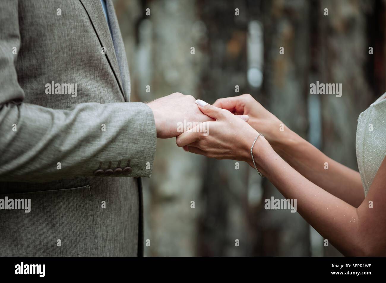 Eine Nahaufnahme einer Braut, die während der Zeremonie sanft einen Ehering auf den Finger des Bräutigams legt. Dieses authentische emotionale Bild ist ideal für Hochzeitsgäste Stockfoto