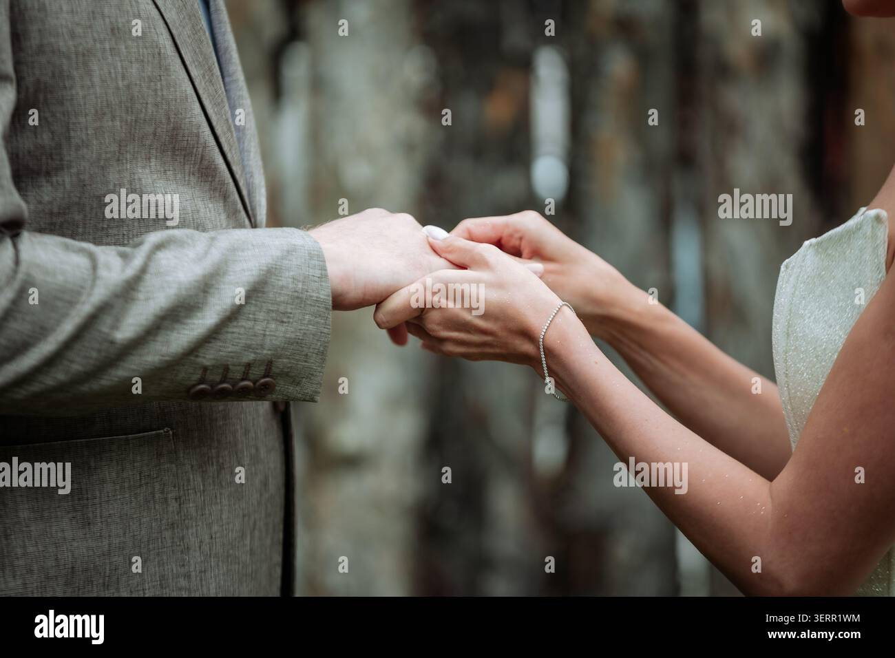 Eine Nahaufnahme einer Braut, die während der Zeremonie sanft einen Ehering auf den Finger des Bräutigams legt. Dieses authentische emotionale Bild ist ideal für Hochzeitsgäste Stockfoto