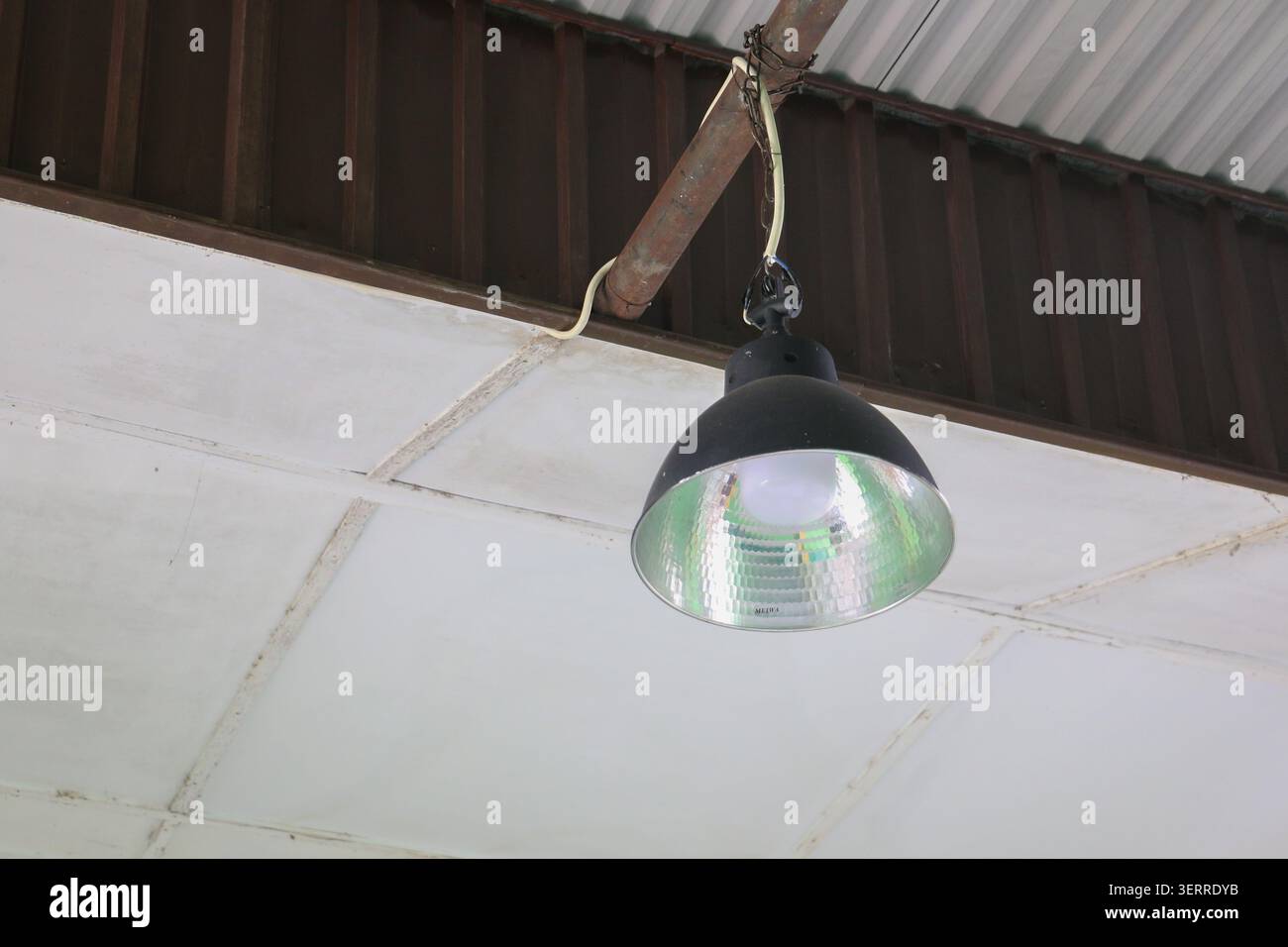 Industrielle LED-Lampe zum Aufhängen unter der Metalldachdecke mit elektrischer Verkabelung, modernes Lager- und Werkstattbeleuchtungskonzept Stockfoto