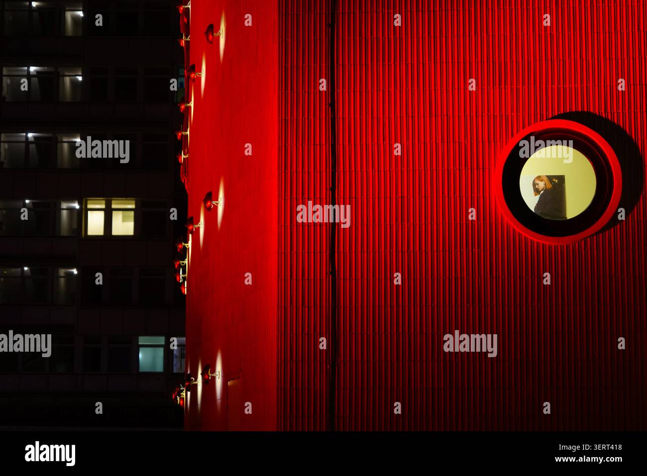 Beleuchtete rote Fassade mit rundem Fenster und Figur, Zoo Palast Kino, Berlin, Nachtstimmung Stockfoto