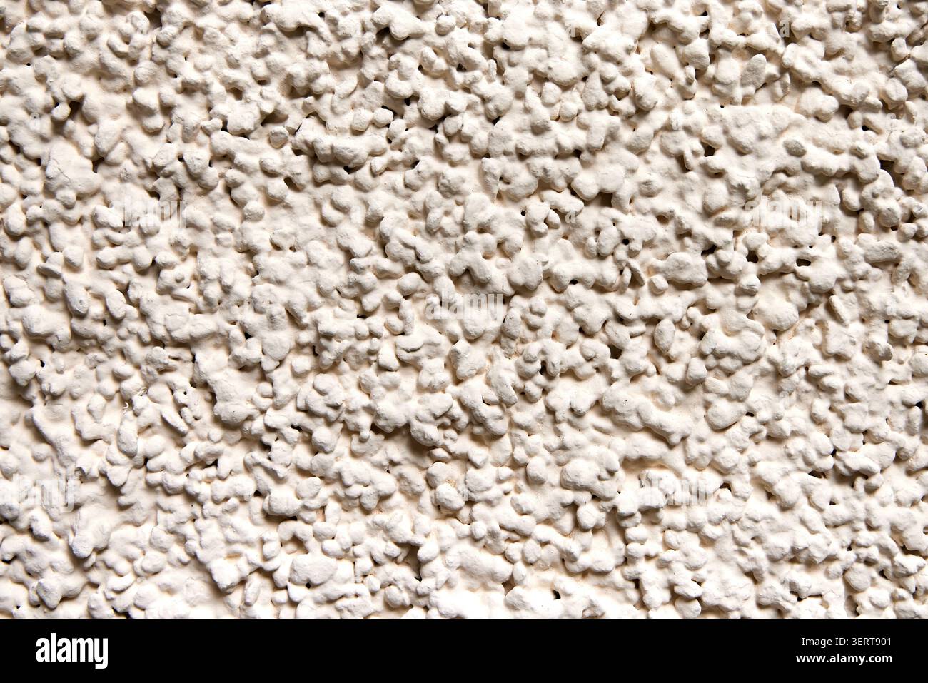 Nahaufnahmetextur aus rauem beigefarbenem Stuckhintergrund mit einem holprigen, kieseligen Strich. Stockfoto