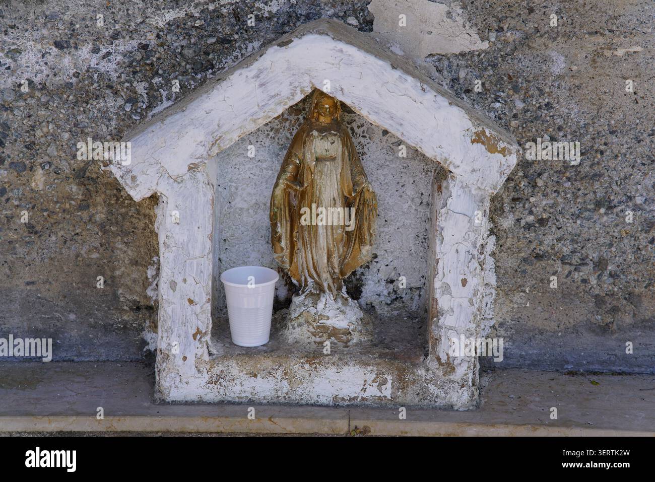 Kleiner Schrein am Straßenrand mit Madonna-Statue auf einer Steinmauer im verlassenen Dorf Ghorio di Roghudi im Nationalpark Aspromonte, Kalabrien, Süditalien. Stockfoto
