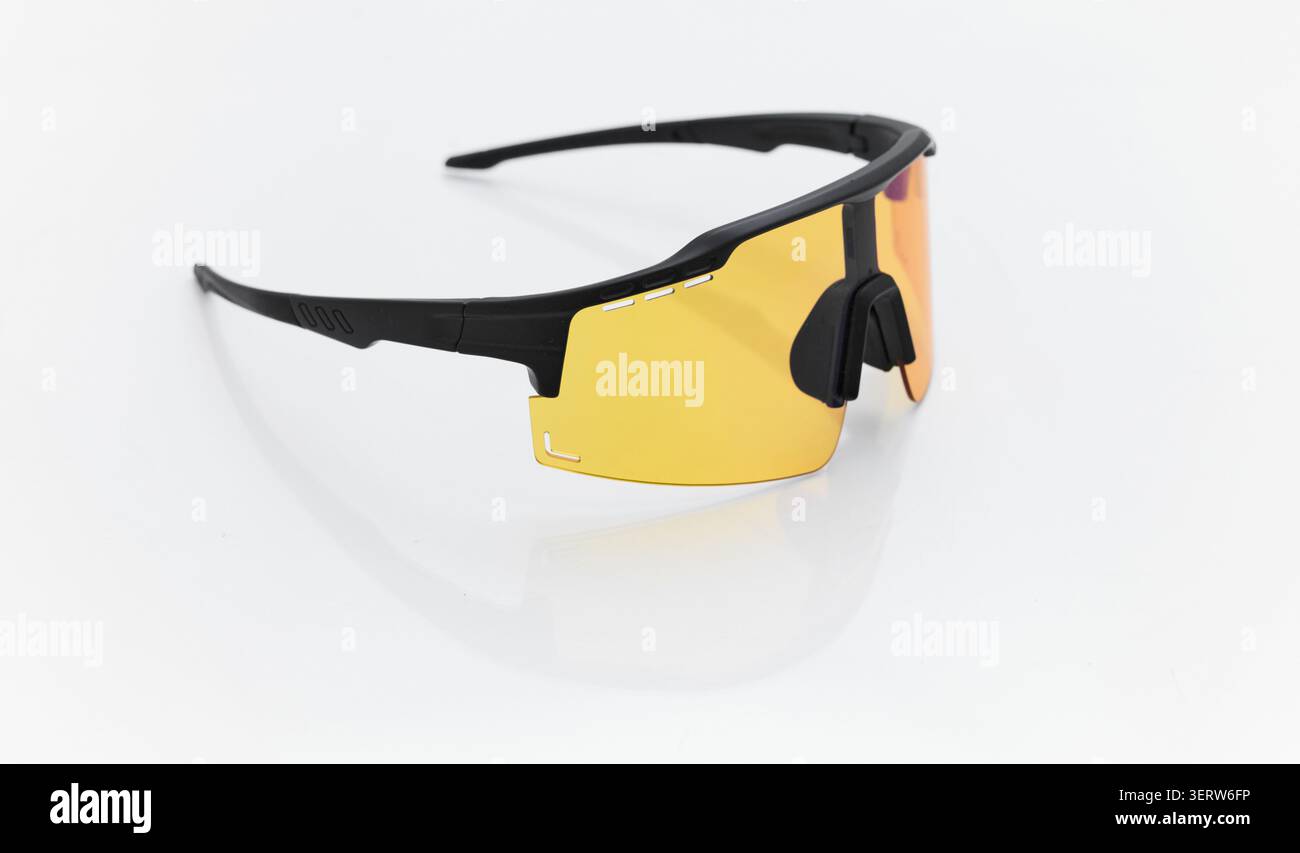 Stilvolle Sonnenbrille auf einem glänzend weißen Tisch, gelbes Glas, schwarzer Sonnenbrillenrahmen, Segelbrille, Radbrille, Reflexion auf einer glänzenden Oberfläche Stockfoto