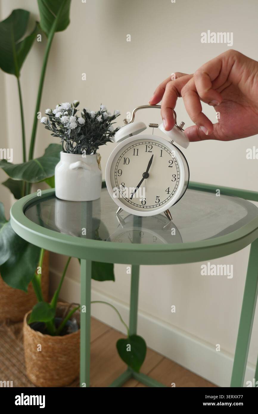 Hand zum Ausschalten des Weckers am Nachttisch Stockfoto