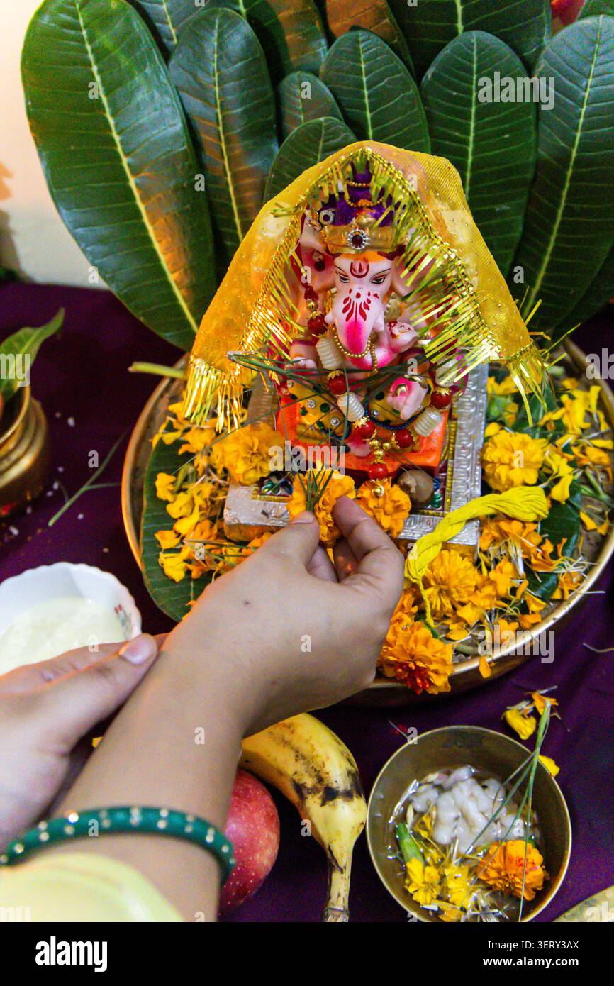 indische Frau, die das ganesha-Kultritual mit dekorativem spirituellem Setup durchführt Stockfoto