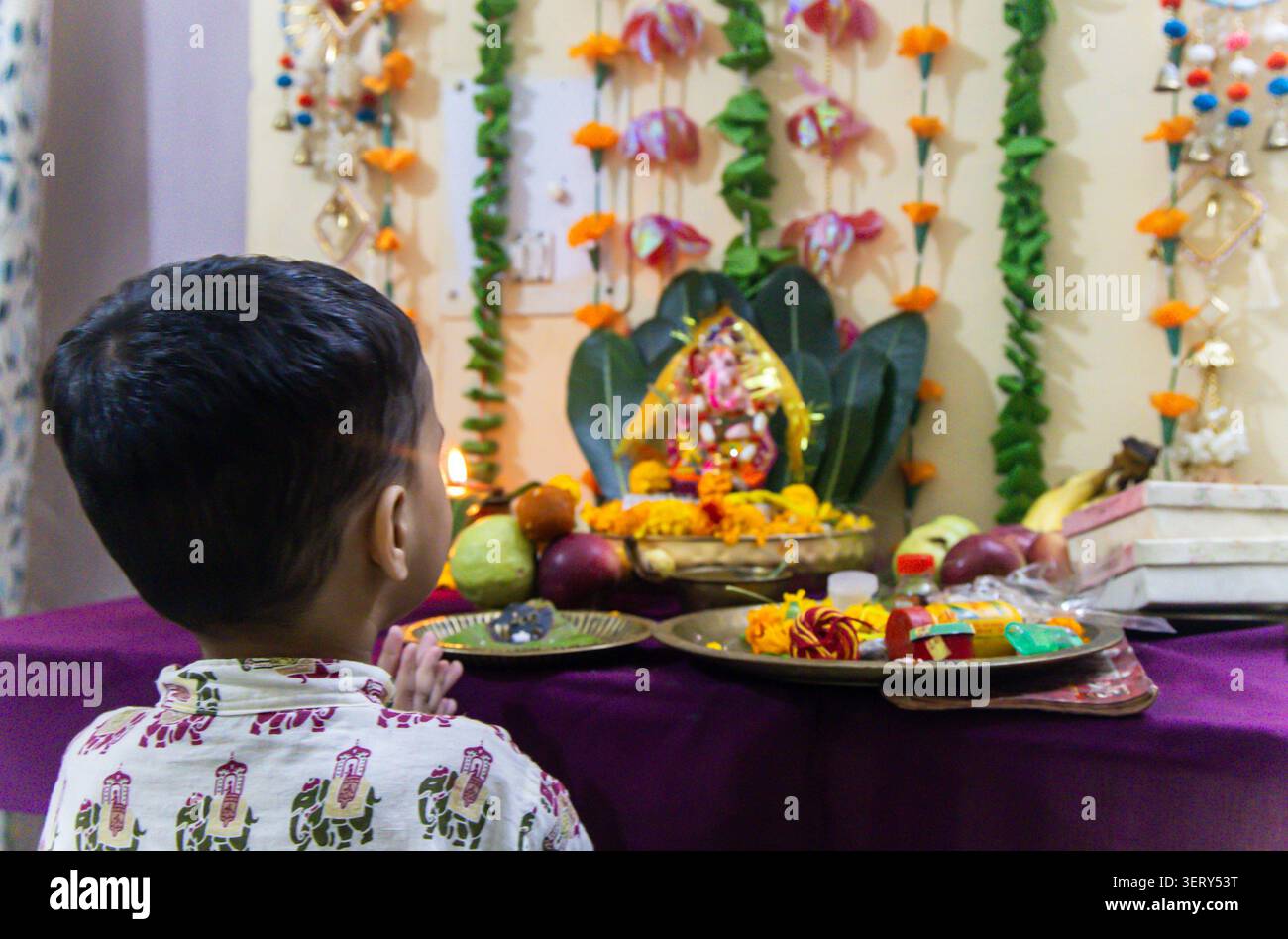 indische Kleinkinder verehren während der Puja Ganpati Bappa in einem dekorierten Tempel Stockfoto