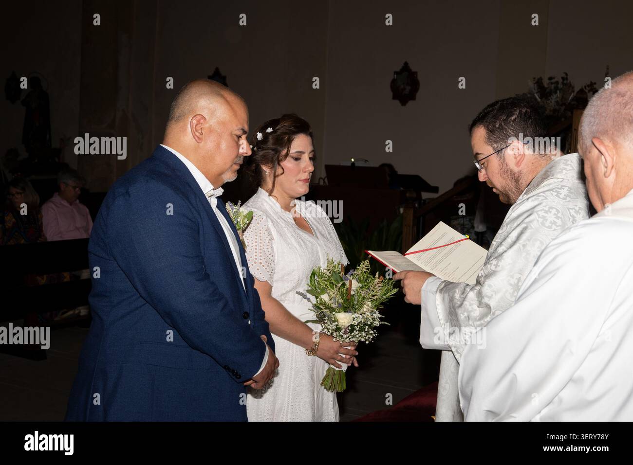 Braut und Bräutigam stehen mit dem Priester während ihrer kirchlichen Hochzeitszeremonie Stockfoto