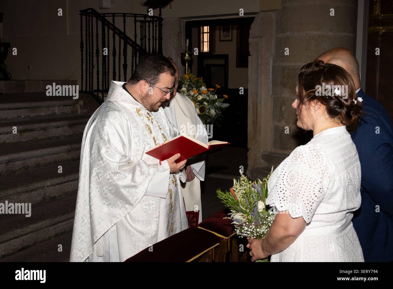 Priester, der eine religiöse Zeremonie für Braut und Bräutigam in einer Kirche durchführt Stockfoto