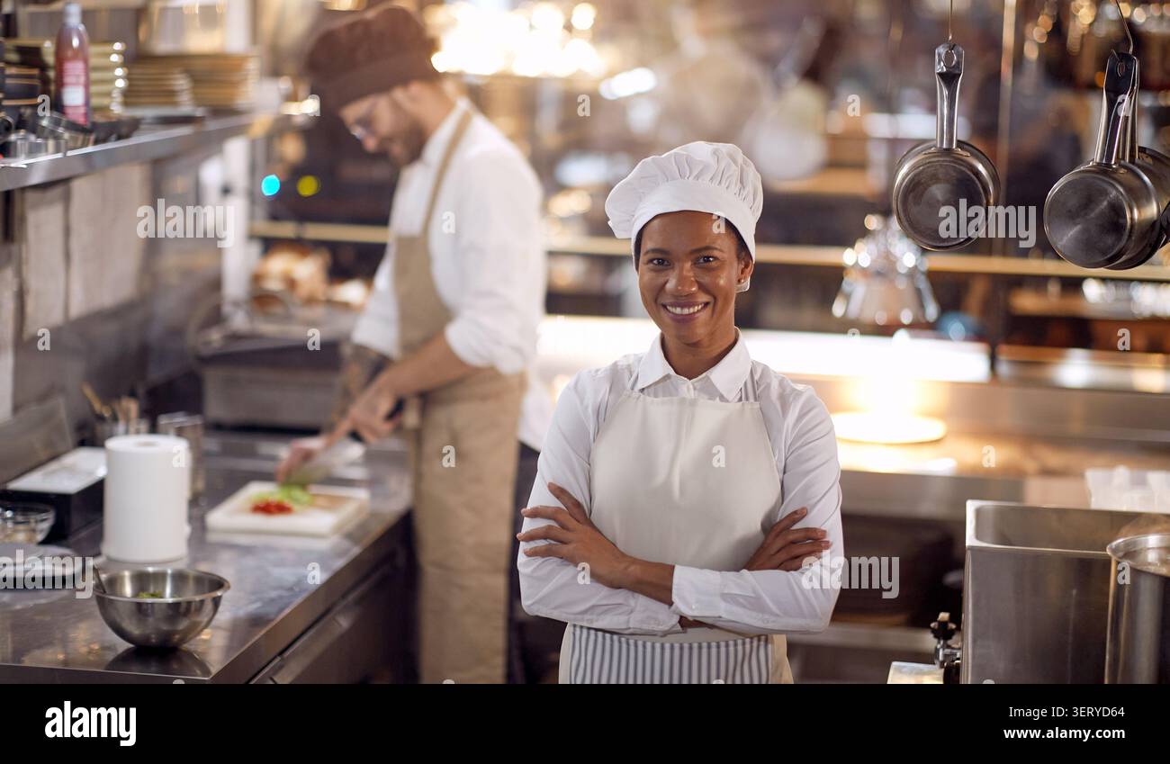Wunderschönes weibliches Porträt der Küchenchefin. Kochen Sie in professioneller, moderner Küche, Restaurant-Konzept Stockfoto