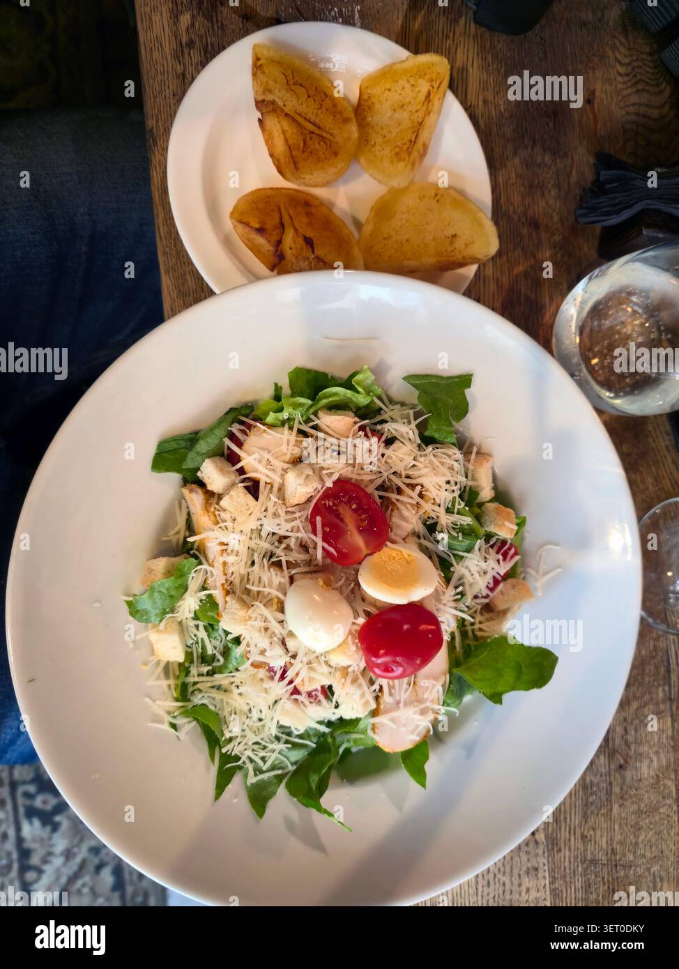 Frischer Caesar-Salat mit hart gekochten Eiern, Kirschtomaten und geröstetem Brot auf Holztable Stockfoto