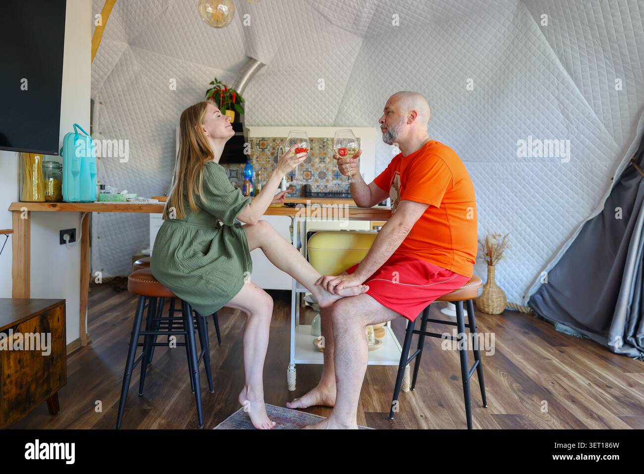 Romantischer Abend in einer modernen geodätischen Kuppel mit einem Paar, das während eines gemütlichen Urlaubs Wein probiert. Stockfoto