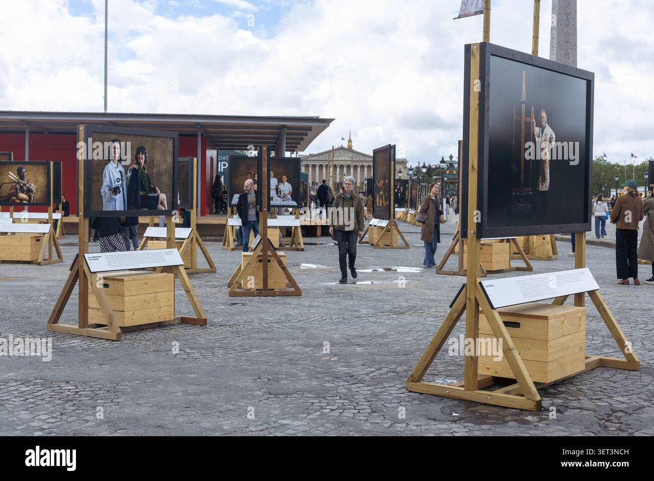 Paris, Frankreich - 3. Mai 2026: Menschen gehen durch einen öffentlichen Platz und sehen sich große Kunstwerke an. Der Platz hat Holzständer und ist umgeben Stockfoto