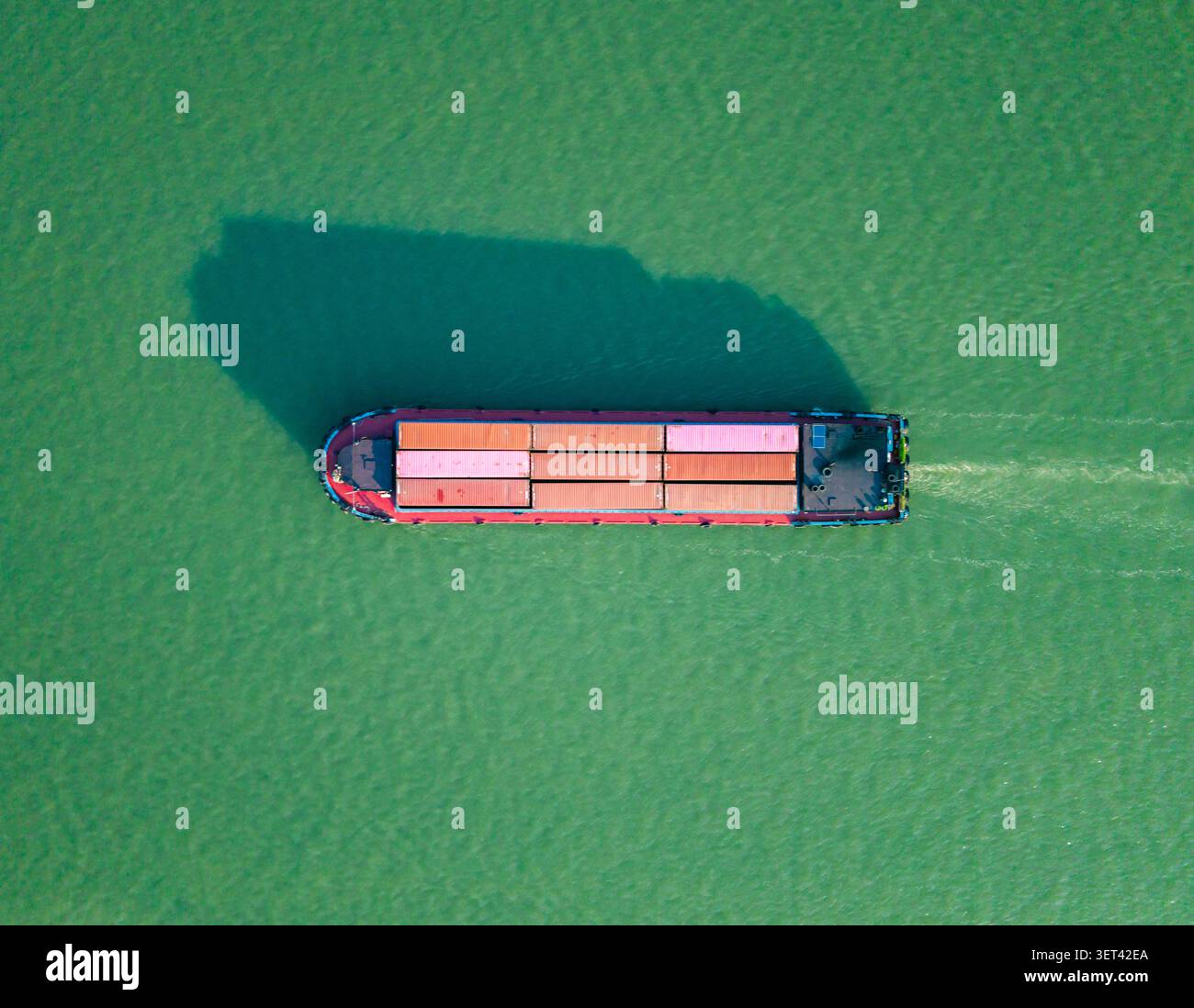 Luftaufnahme von oben nach unten auf das Containerschiff navigiert bei hellem Tageslicht in ruhigen Gewässern in der Nähe der Küste. Hangzhou, China. Stockfoto