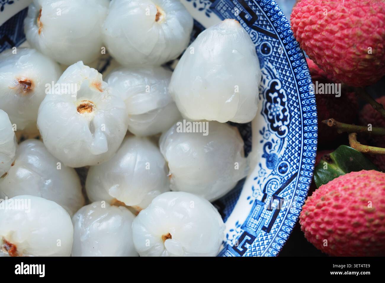 Frisches Litschi-Obst in einer Schüssel in der Nähe von mehr Litschi Stockfoto