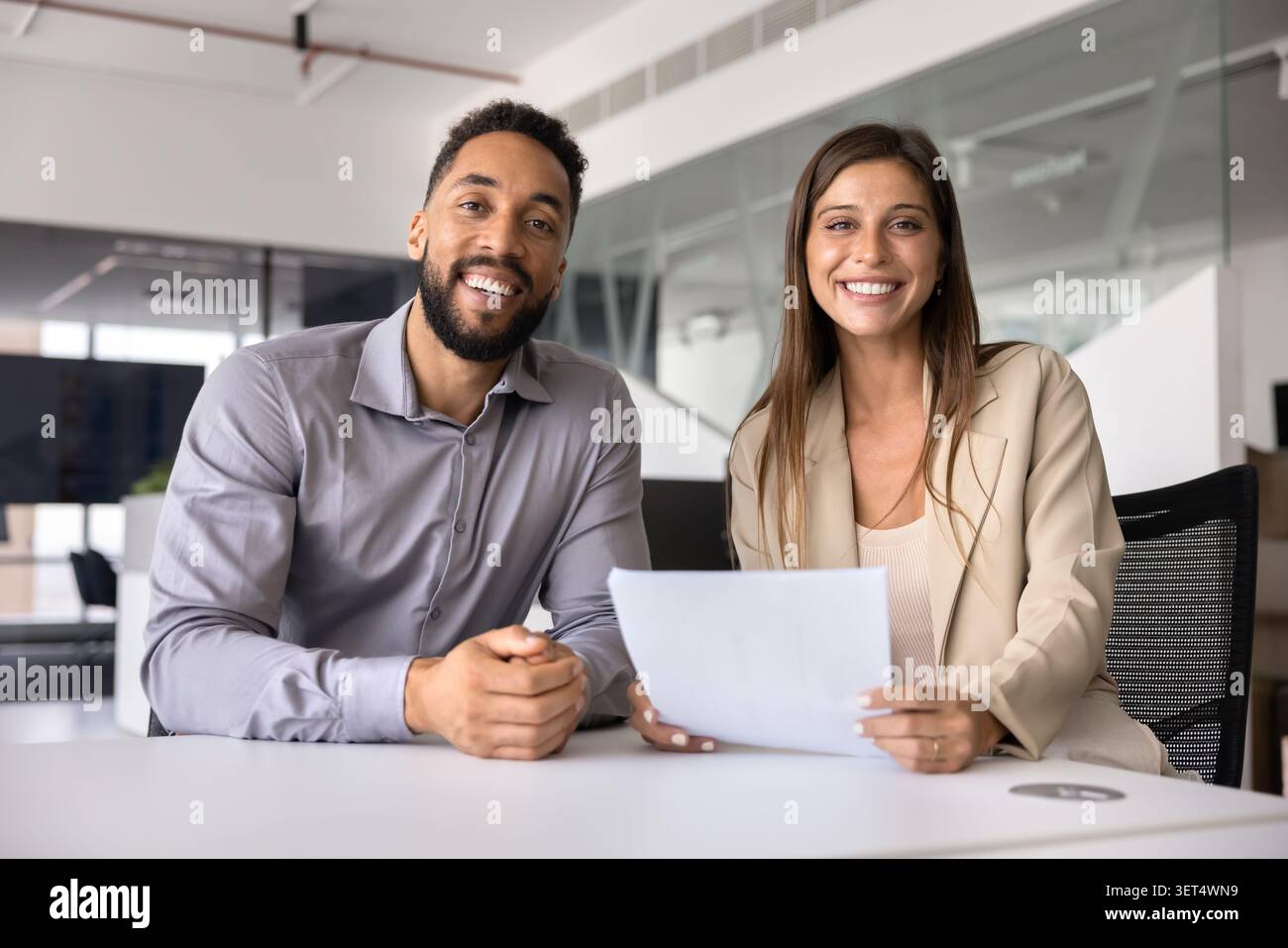 Zwei freundliche Kollegen posieren gemeinsam in einem modernen Büro Stockfoto