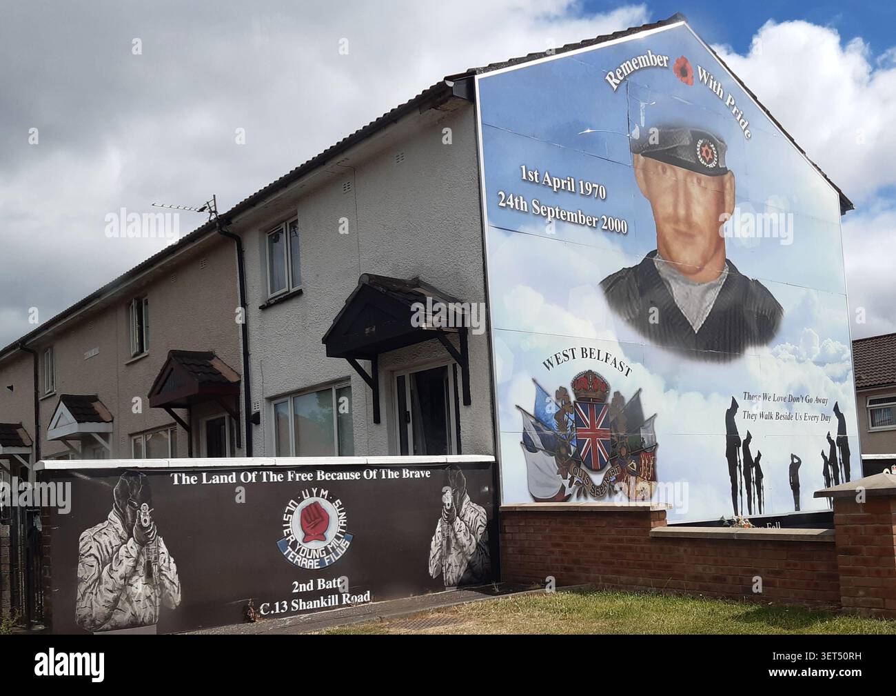 Wandgemälde mit einem Soldaten und militärischen Bildern an einer Wohnwand in West Belfast, Nordirland, zum Gedenken an vergangene Konflikte und Dienste. Stockfoto
