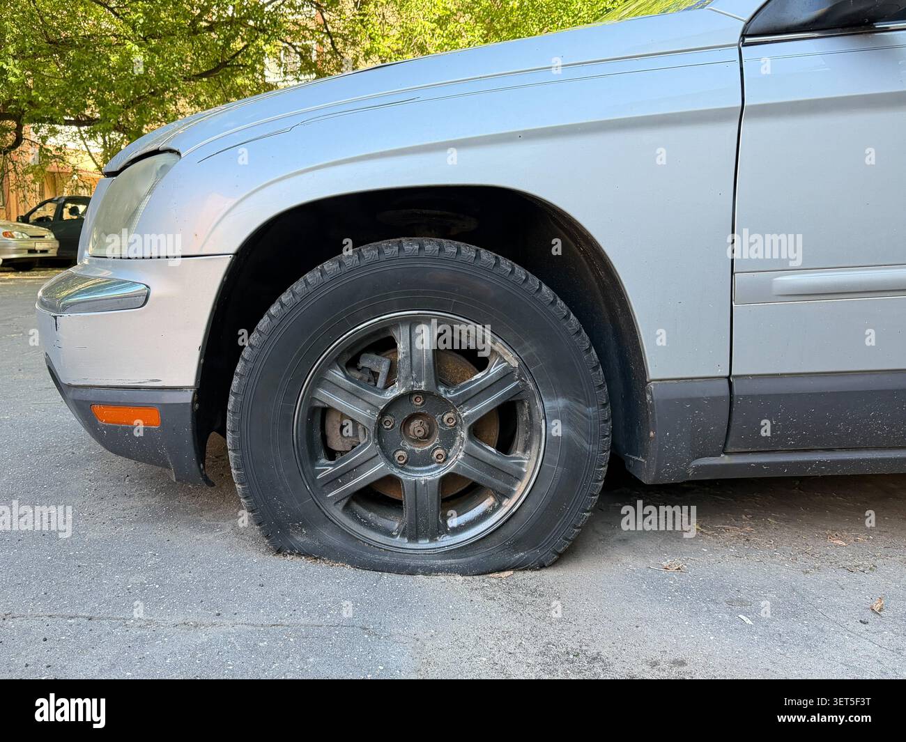 Platter Reifen auf geparkten silbernen Pkw-Ständen auf Stadtstraßen, Probleme mit der Fahrzeugwartung, Transportstörungen, Sicherheit am Straßenrand. Kfz-Service Stockfoto