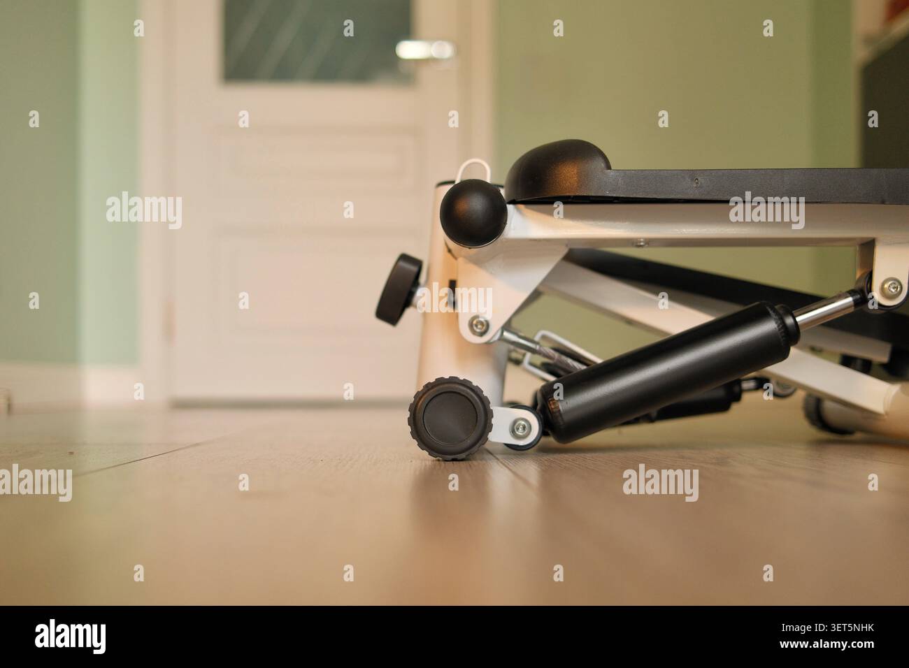 Kompakter Mini-Stepper-Übungsgerät auf Holzboden zu Hause. Konzept der Home Fitness, gesunde Lebensweise, Cardio-Workouts, Gewichtsverlust Stockfoto