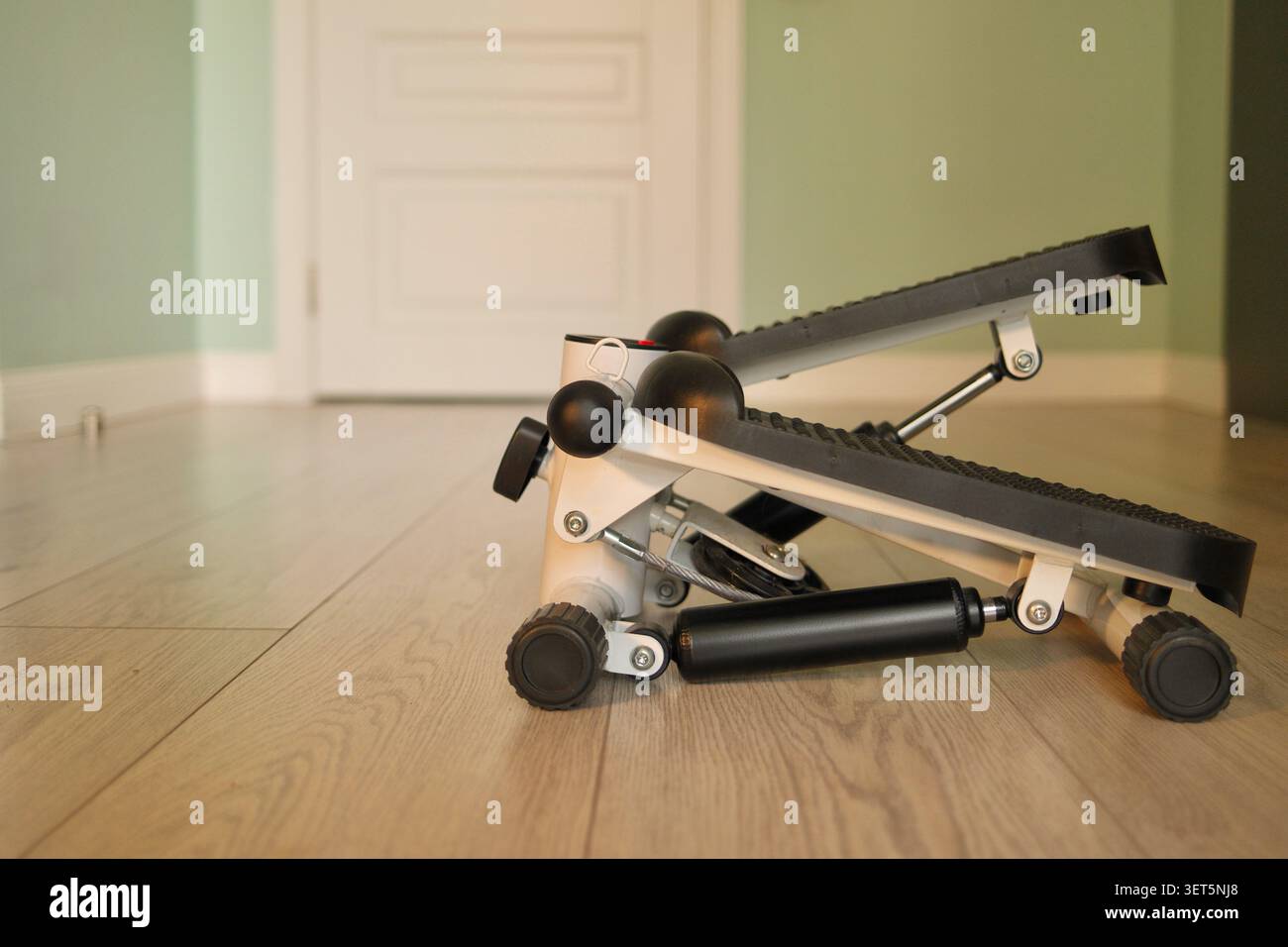 Kompakter Mini-Stepper-Übungsgerät auf Holzboden zu Hause. Konzept der Home Fitness, gesunde Lebensweise, Cardio-Workouts, Gewichtsverlust Stockfoto