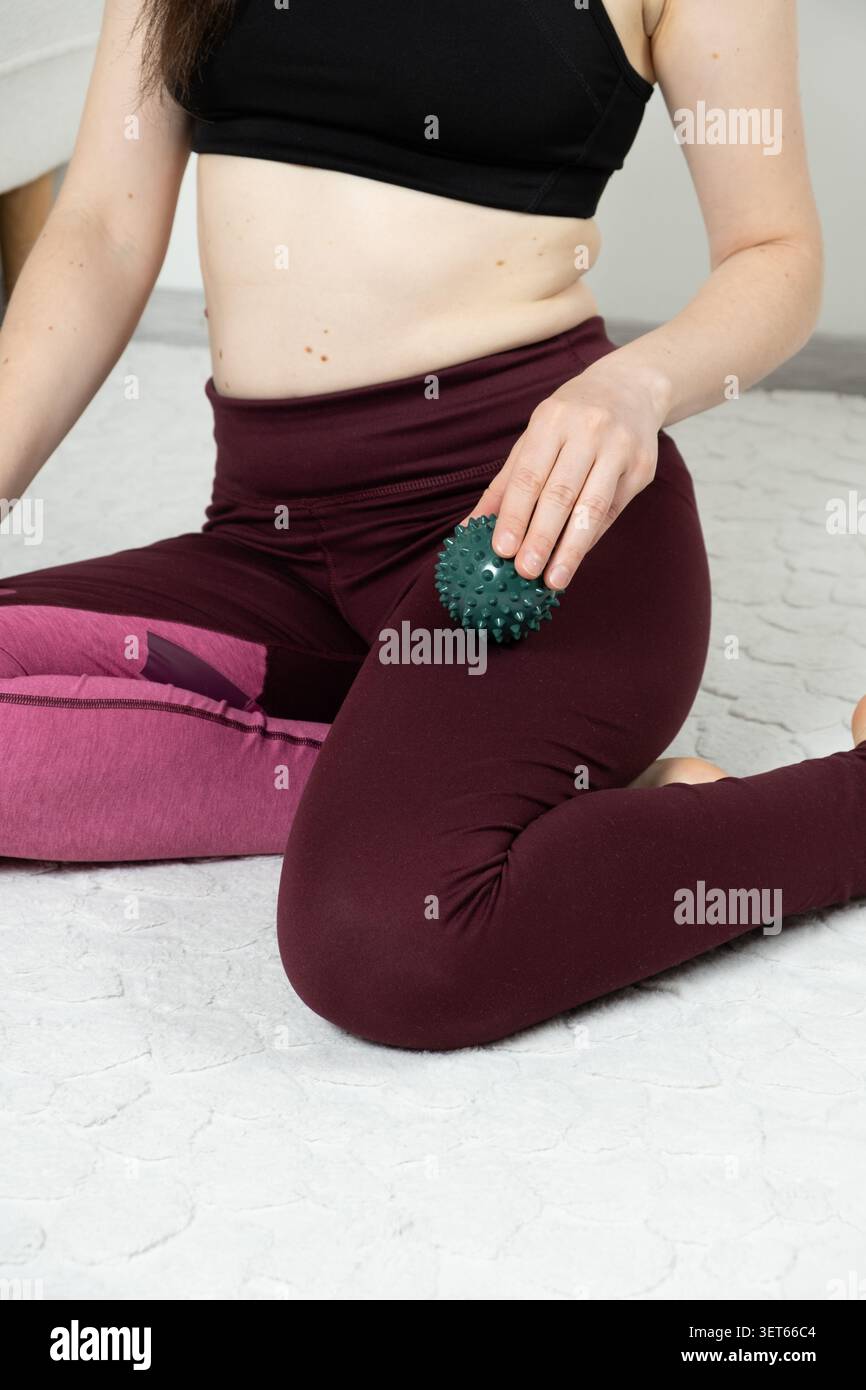 Frau in Sportbekleidung mit Triggerpunkt-Ball zur Erholung der Beinmuskulatur Stockfoto