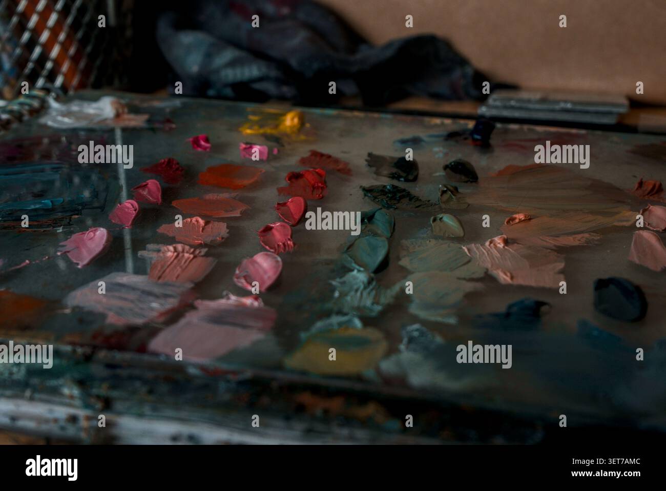 Eine Palette von Glasölmalern mit gemischten Farben, die nach Schattierungen in Rosa, Grün und weichen Orangen sortiert sind. Stockfoto