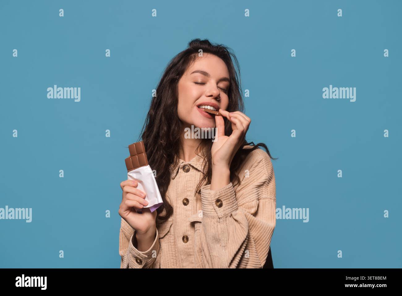 Happy Young Woman Genießt Schokoladenbar, Lächeln, Kopierraum, Snackkonzept Stockfoto