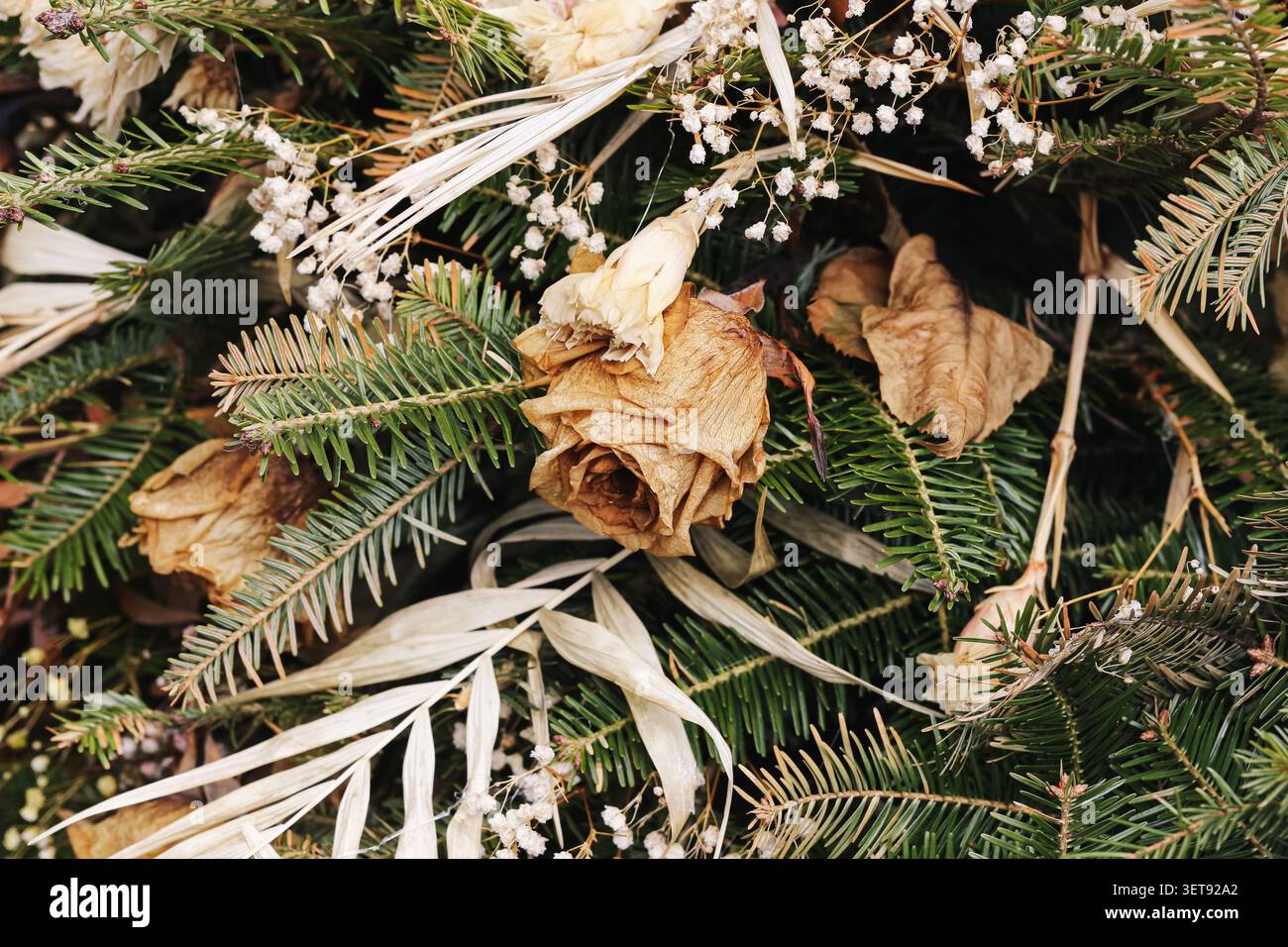 Rustikaler Gedenkkranz mit getrockneten Blumen und immergrünen Zweigen. Natürlicher Dekorationshintergrund für Erinnerungstraditionen und Friedhofsbesuche. Stockfoto