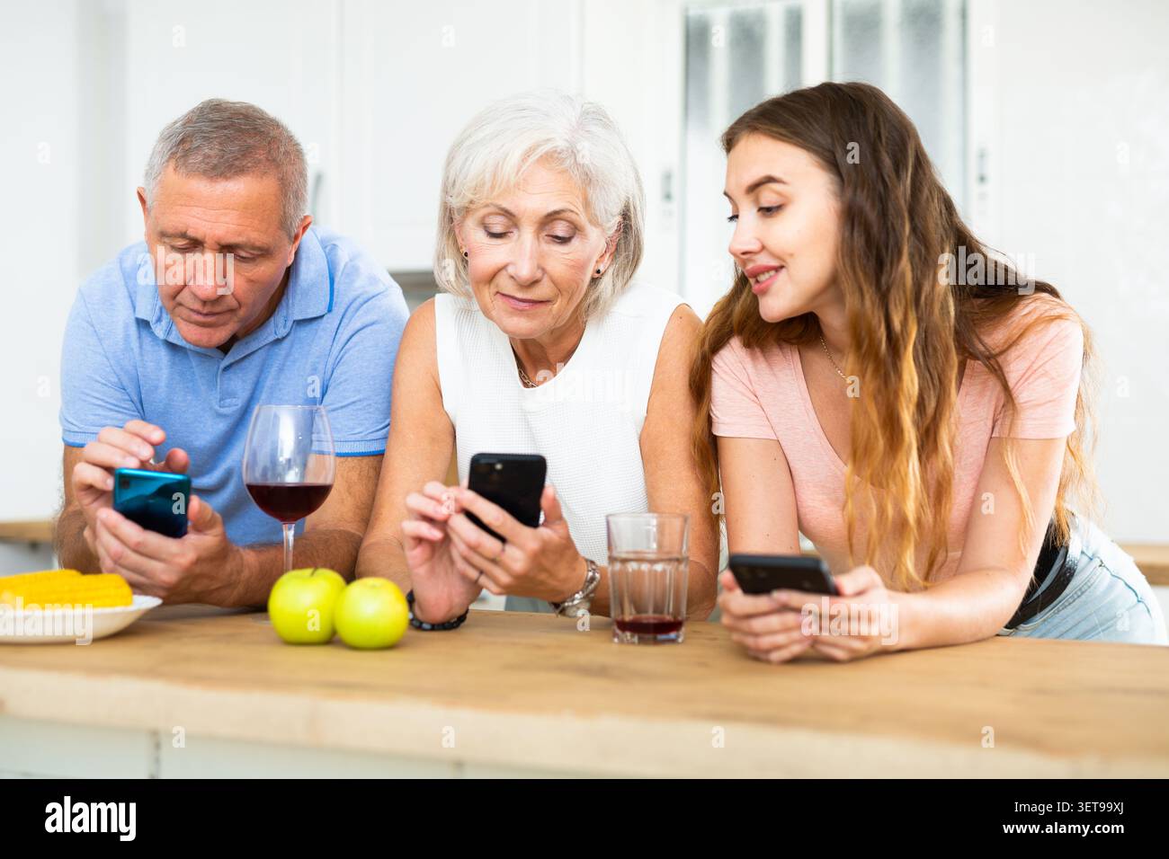 Porträt der Familie, die während des Essens im Haus telefoniert Stockfoto