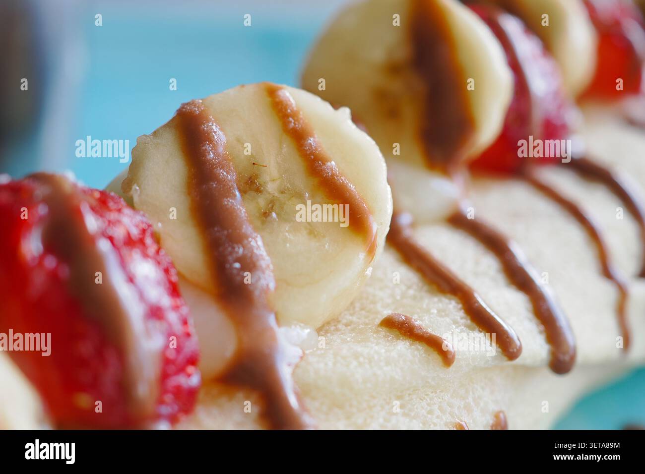 Köstliches Dessert mit Banane und Erdbeeren auf einem Teller Stockfoto