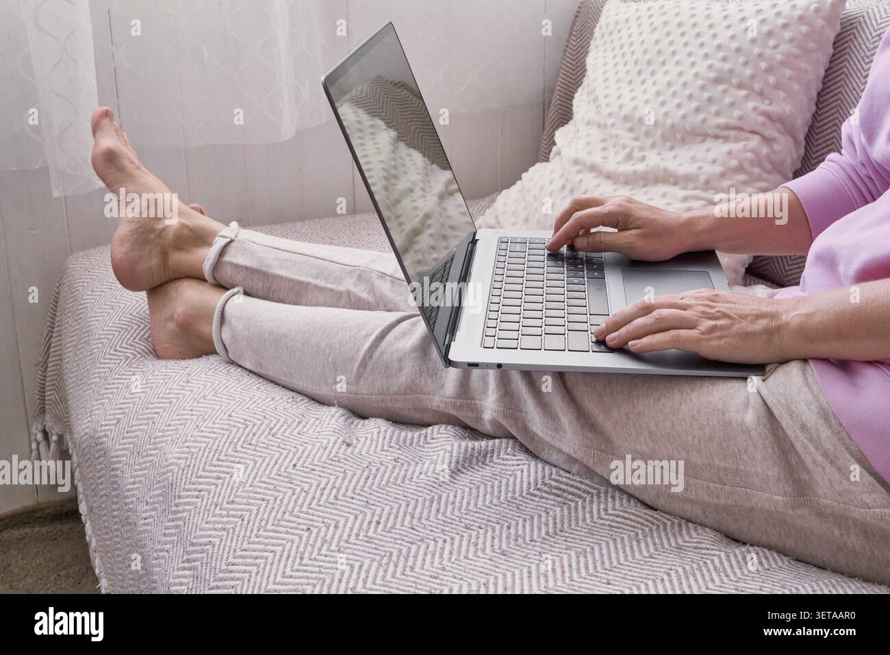 Kaukasische Frau, die sich zu Hause auf dem Sofa mit Laptop entspannt Stockfoto