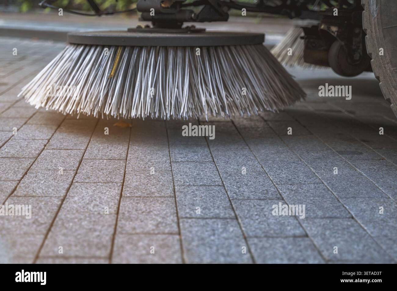 Die Bürste der mechanischen Straßenkehrmaschine berührt den Boden während der Stadtreinigung. Konzept der kommunalen Regierungsdienste, Hygienestandards und der modernen Stadt Stockfoto