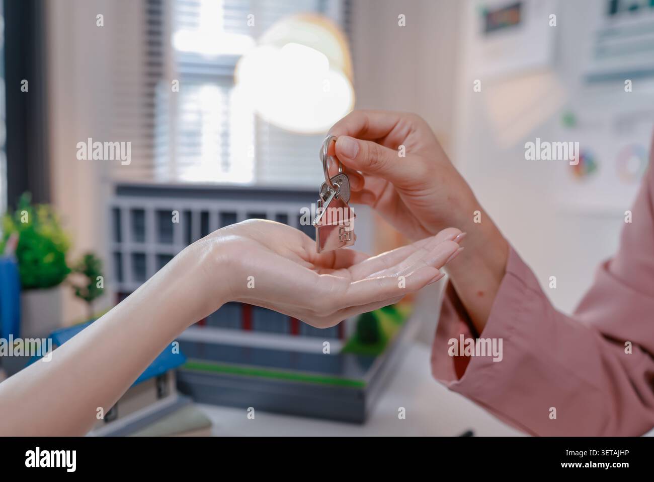 Immobilienmakler prüft Immobiliendokumente und Versicherungsunterlagen mit einem Kunden, bevor er Hausschlüssel übergibt, was eine erfolgreiche privatperson darstellt Stockfoto