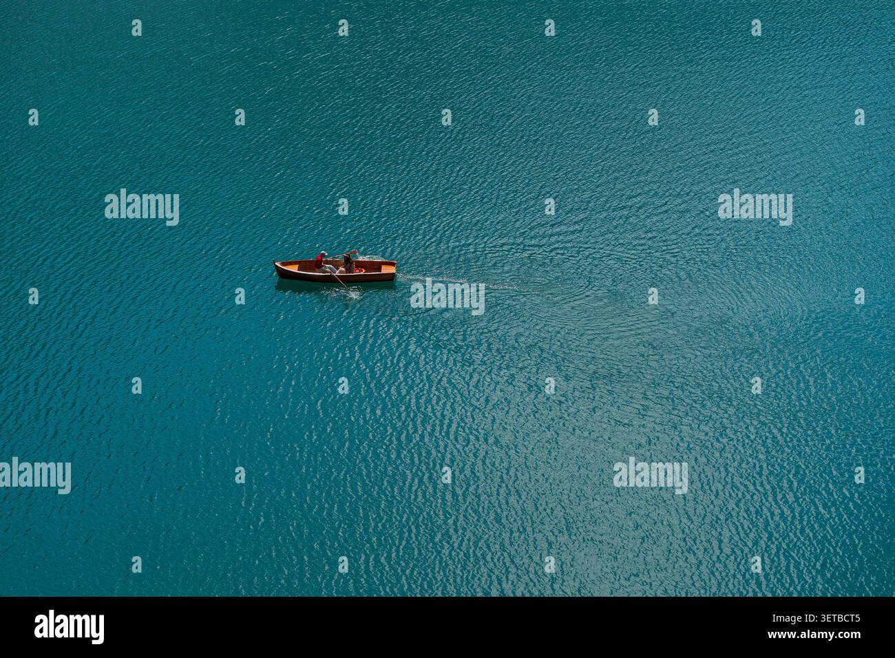 Blick aus der Höhe auf ein kleines hölzernes Ruderboot mit Touristen, die über lebendiges türkisfarbenes Wasser gleiten, friedliche Sommerreise und Seekonzept. H Stockfoto