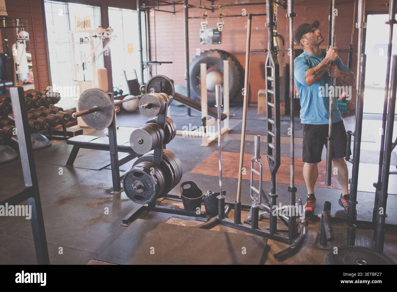 Ein Mann, der beim Training im Fitnessstudio die Bar vom Rack auswählt Stockfoto