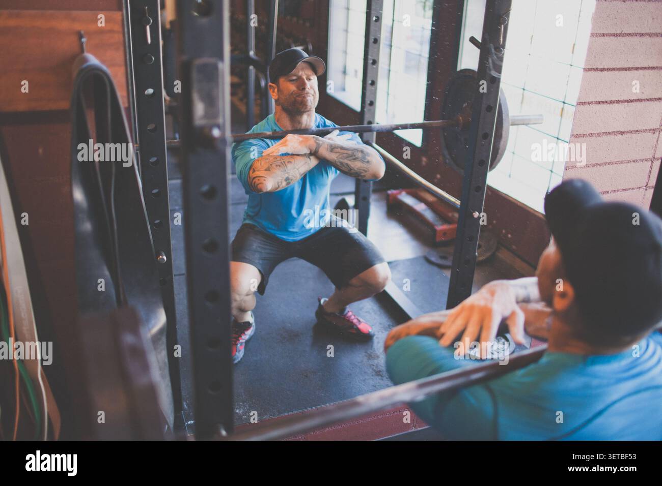 Tätowierter Mann, der im Fitnessraum die Vorderhosen vorzieht Stockfoto