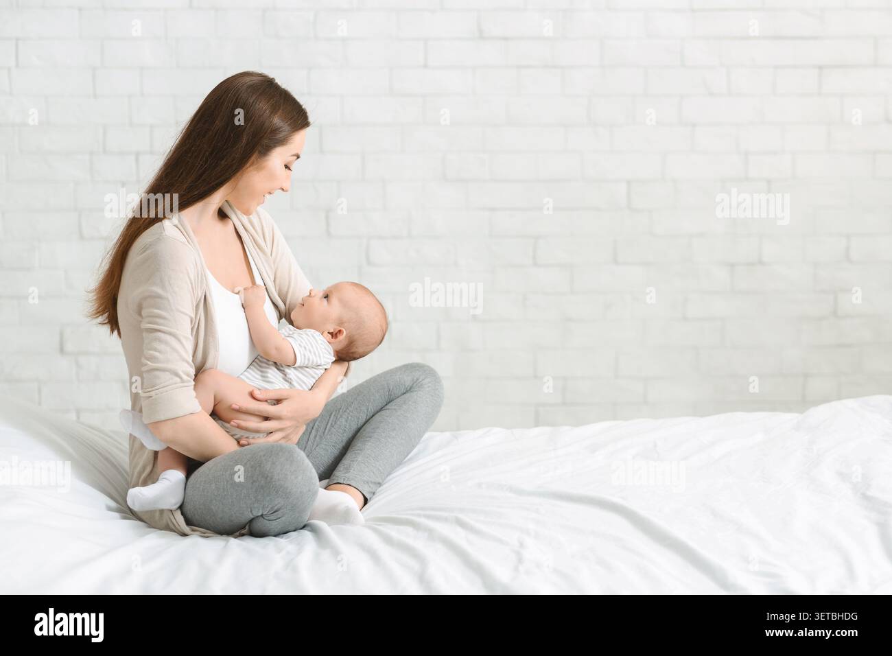 Mutter stillt ihr Baby in einer ruhigen Innenumgebung im Morgenlicht Stockfoto