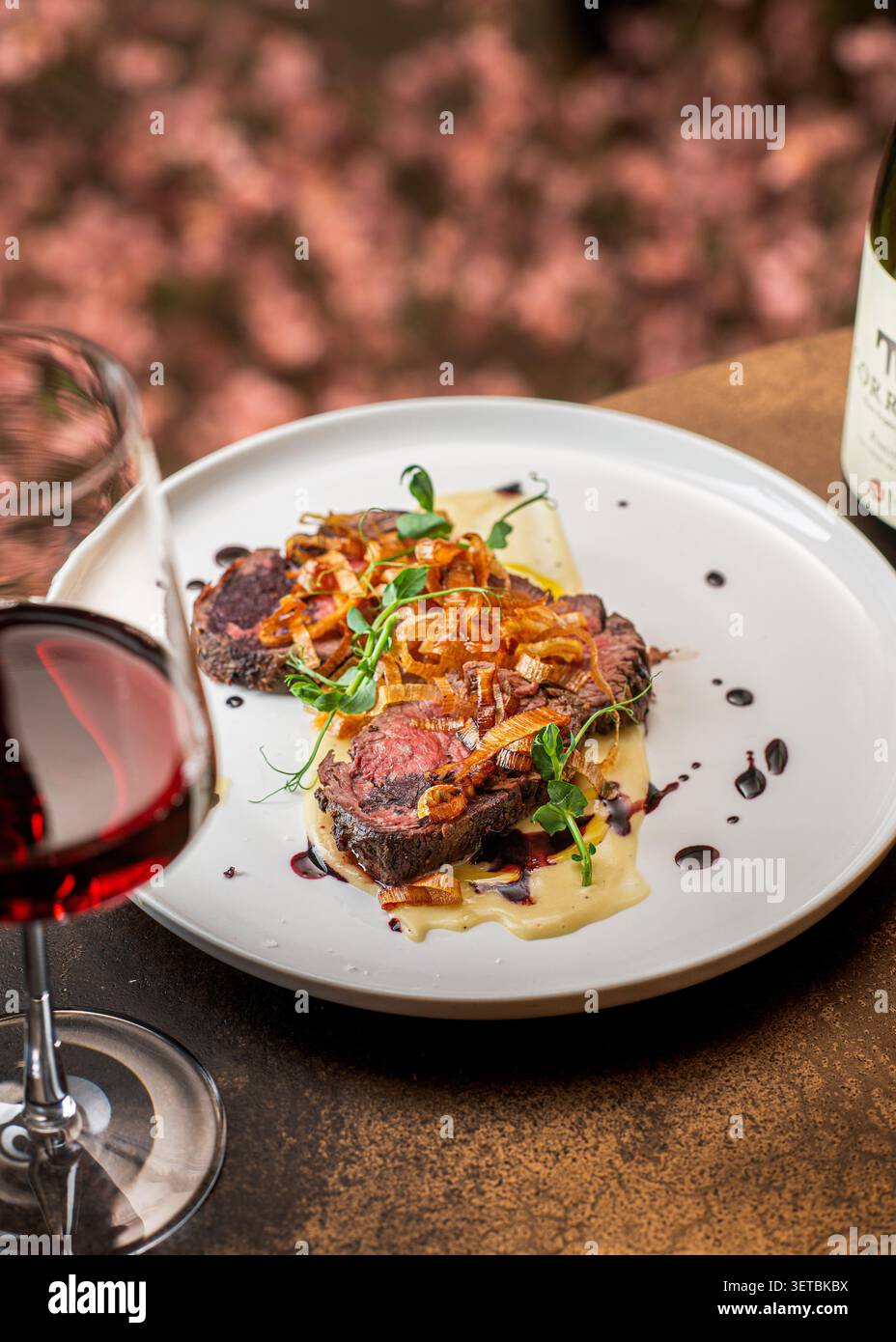 Mittelseltene Rindermedaillons auf Kartoffelpüree, garniert mit knusprigem gebratenem Lauch und Rotweinreduktion. Stockfoto