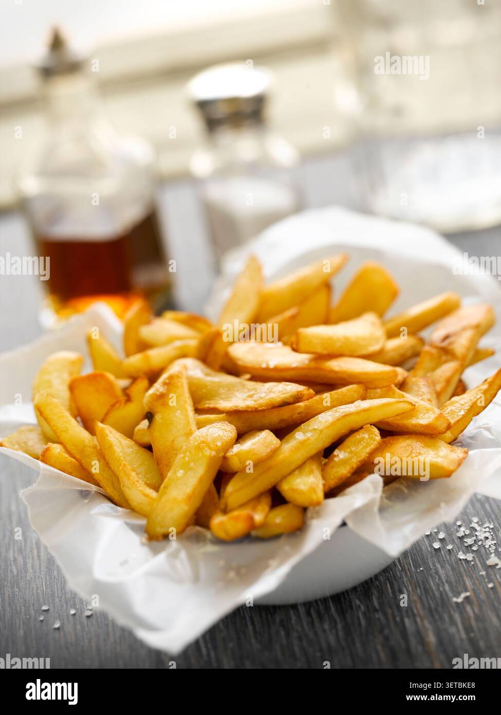 Nahaufnahme knuspriger goldener Pommes frites in einer Schüssel mit Papier Stockfoto