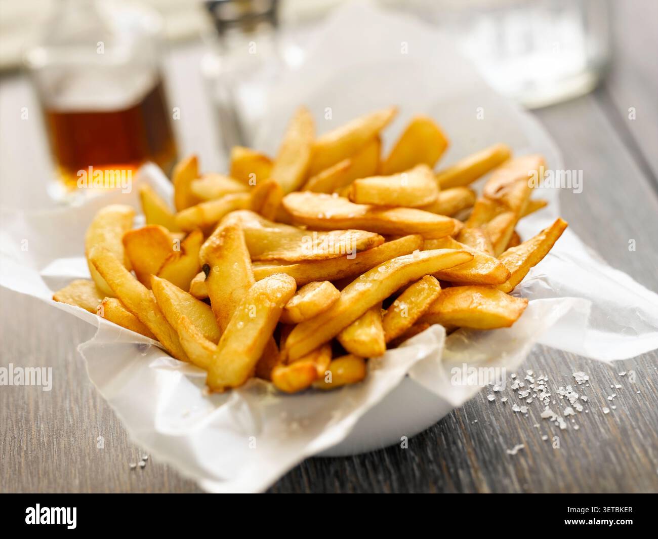Nahaufnahme knuspriger goldener Pommes frites in einer Schüssel mit Papier Stockfoto