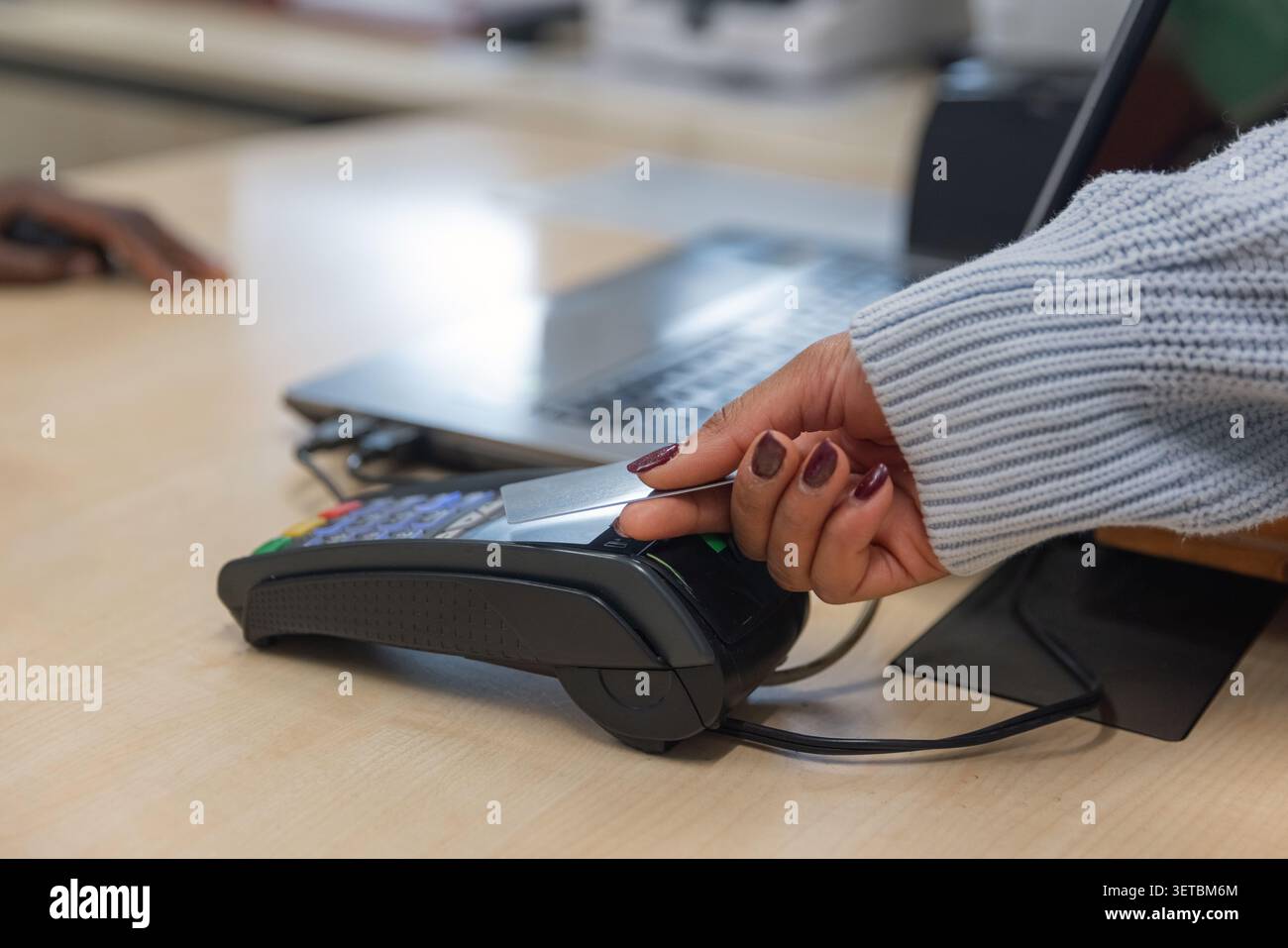 Der Kunde bezahlt für den Service mit kontaktloser Kreditkarte an einem POS-Terminal. Stockfoto